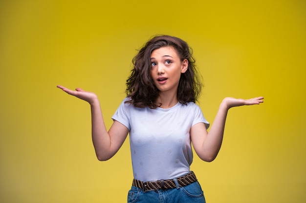 Jeune fille faisant face stupide avec les mains ouvertes.