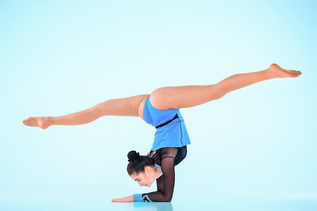 La jeune fille faisant de la gymnastique danse sur fond bleu