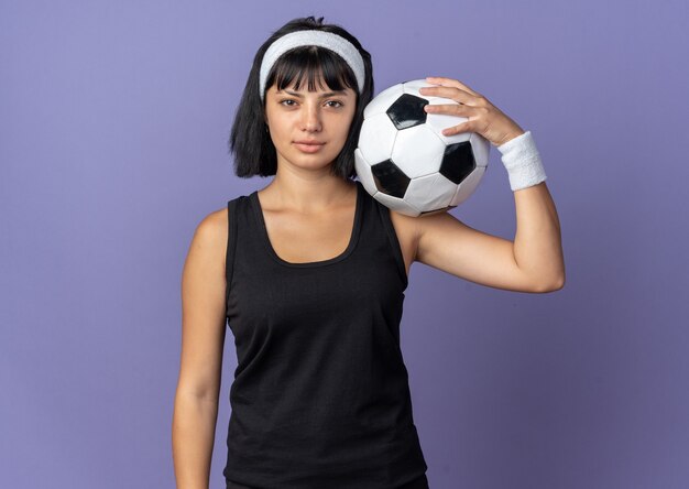 Jeune fille fitness portant un bandeau regardant la caméra avec une expression sérieuse et confiante