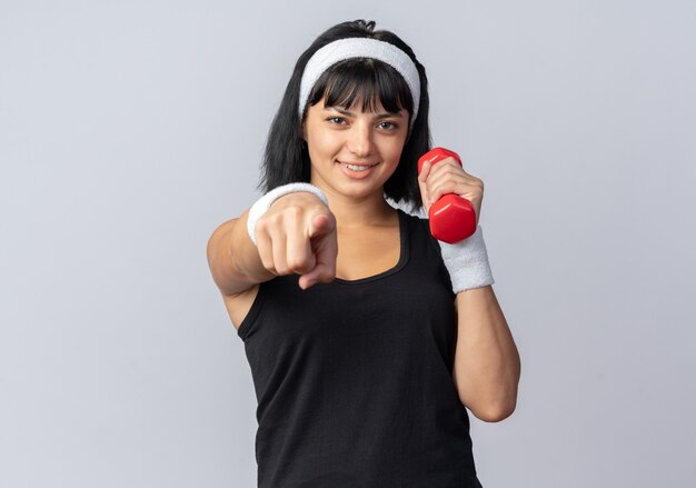 Jeune fille fitness portant un bandeau tenant un haltère faisant des exercices à la confiance