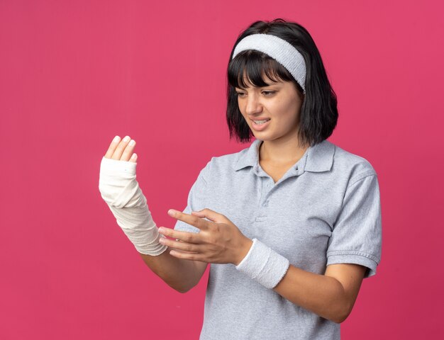 Jeune fille fitness portant un bandeau touchant sa main bandée à la sensation de malaise