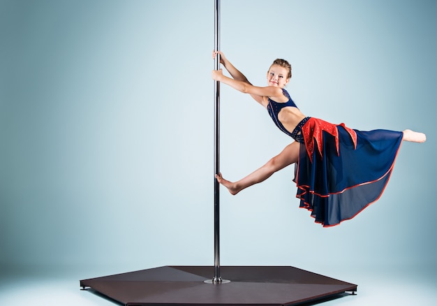 Photo gratuite la jeune fille forte et gracieuse effectuant des exercices acrobatiques sur pylône