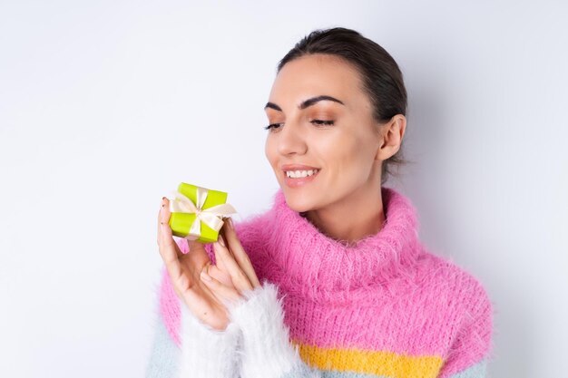 Jeune fille gaie dans un chandail de couleur douce sur fond blanc contient de petites boîtes-cadeaux mignonnes