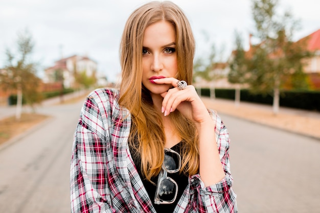 Jeune fille gaie jolie blonde avec un visage surpris à la recherche, posant dans la campagne en journée de printemps chaude et ensoleillée. Visage émotionnel drôle.