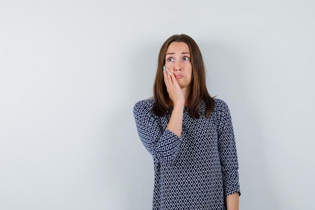 Une jeune fille d'humeur triste a mis sa main sur sa joue