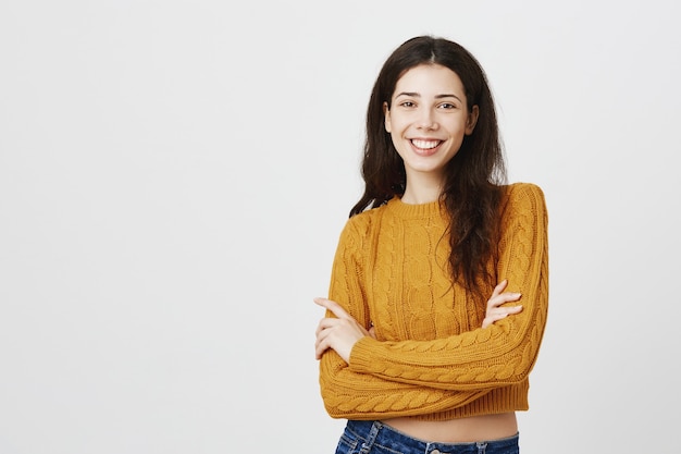 Jeune fille impertinente poitrine croisée et souriant montrant la confiance