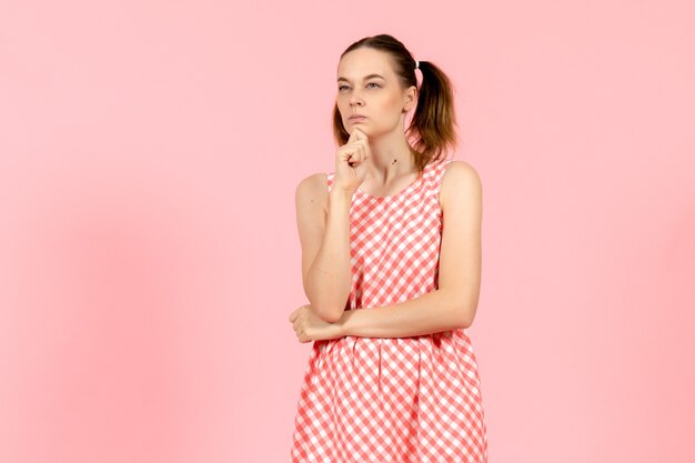 jeune fille en jolie robe lumineuse avec une expression de pensée sur rose