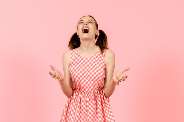 Jeune fille en jolie robe rose crier en colère sur rose