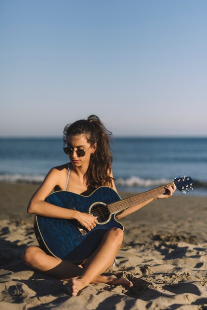 Jeune fille joue de la guitare à la plage