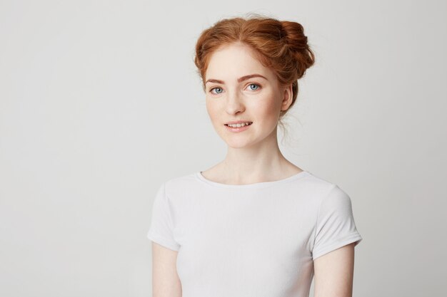 Jeune fille joyeuse gingembre heureux avec des petits pains et des taches de rousseur souriant.