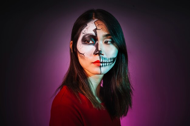 Jeune fille avec le maquillage et le masque de halloween