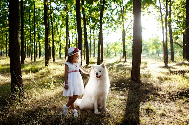 Jeune fille marchant, jouant avec un chien dans le parc au coucher du soleil.