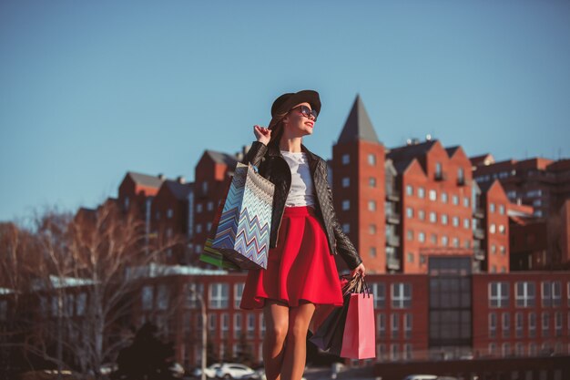 La jeune fille marche avec shopping dans les rues de la ville