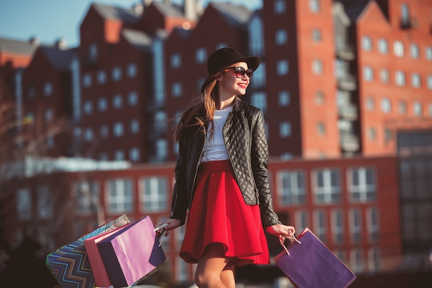 La jeune fille marche avec shopping dans les rues de la ville