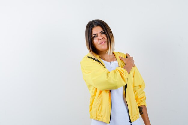 Jeune fille mettant la main sur l'épaule en t-shirt blanc, veste jaune et à la hâte. vue de face.