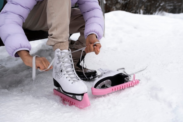 Photo gratuite jeune fille mettant ses patins à glace à l'extérieur en hiver