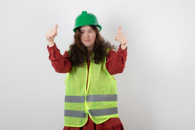 jeune fille mignonne debout dans un casque vert et montrant les mains en l'air.