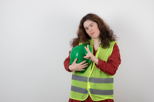 jeune fille mignonne avec le syndrome de Down debout en gilet montrant le signe de la victoire.