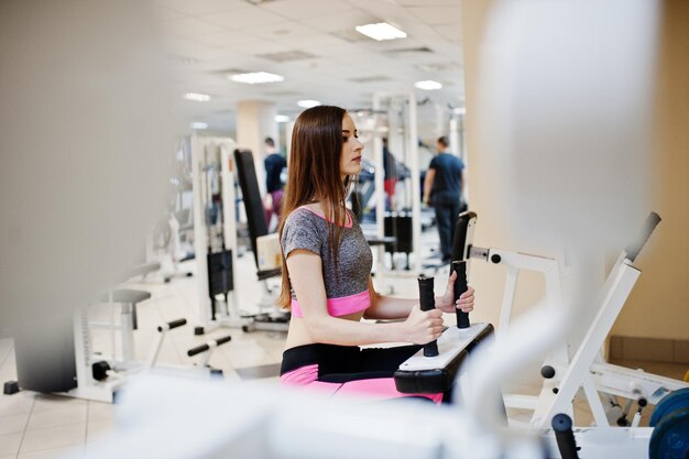 Jeune fille mince sexy brune faisant de l'exercice au gymnase