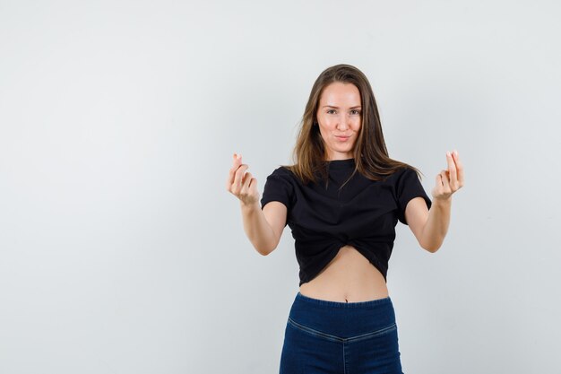 Jeune fille montrant le signe de l'amour coréen en chemisier noir, pantalon et à la joyeuse