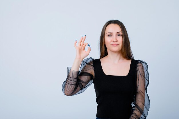 Jeune fille montre un geste correct en regardant la caméra sur fond blanc