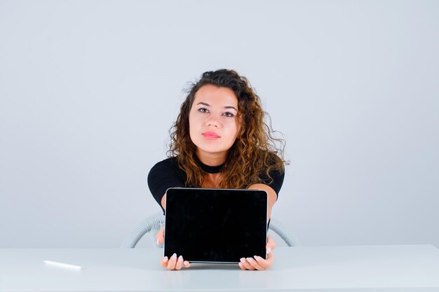 Jeune fille montre une idée de maquette avec une tablette sur fond blanc