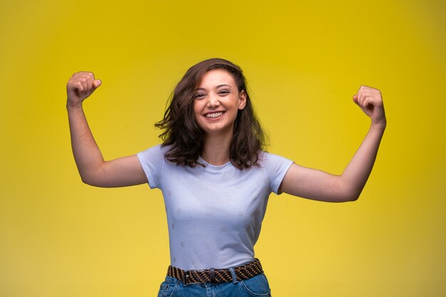 Jeune fille montre ses muscles du bras et souriant.