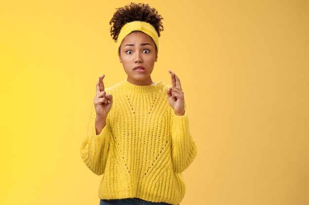 Une jeune fille nerveuse, incertaine, hésitante, espère avoir de la chance, croiser les doigts, se mordre la lèvre, inquiète, regarder avec anxiété la caméra, peur de mauvais résultats, attendre des nouvelles importantes, espérer recevoir une bourse, gagner à la loterie.