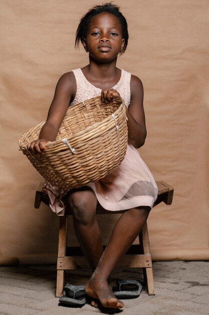 Jeune fille avec panier de paille assis sur une chaise