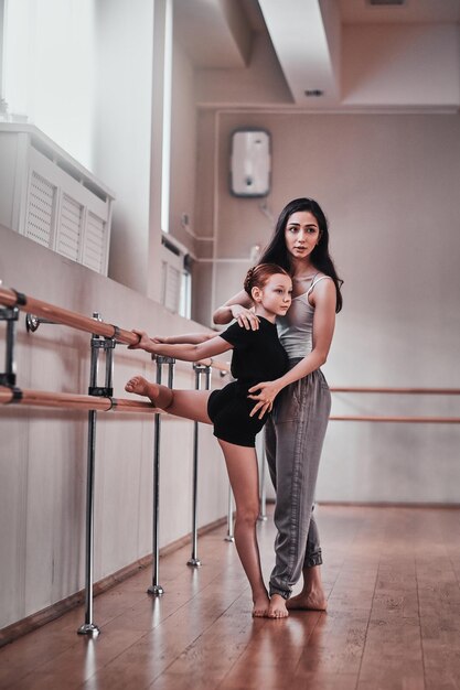 Une jeune fille pensive a eu une répétition spéciale de ballet d'un entraîneur diligent joyeux dans une salle d'entraînement lumineuse.