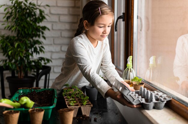 Jeune fille plantant des graines par la fenêtre