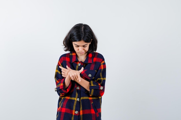 Jeune fille pointant avec l'index, regardant vers le bas en chemise à carreaux et l'air sérieux. vue de face.