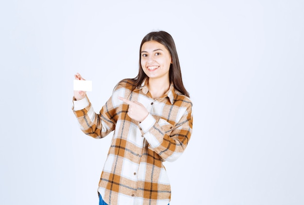 jeune fille pointant sur une tasse de thé sur un mur blanc.