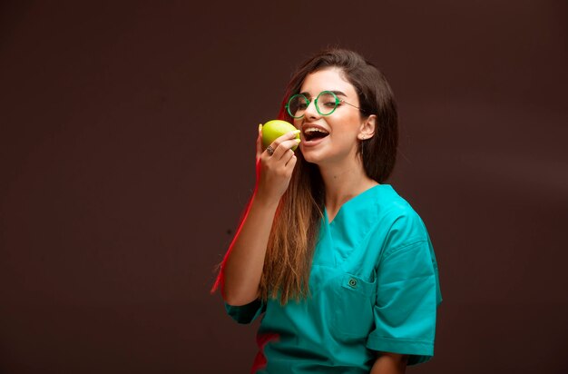 Jeune fille avec une pomme verte dans la main de manger.