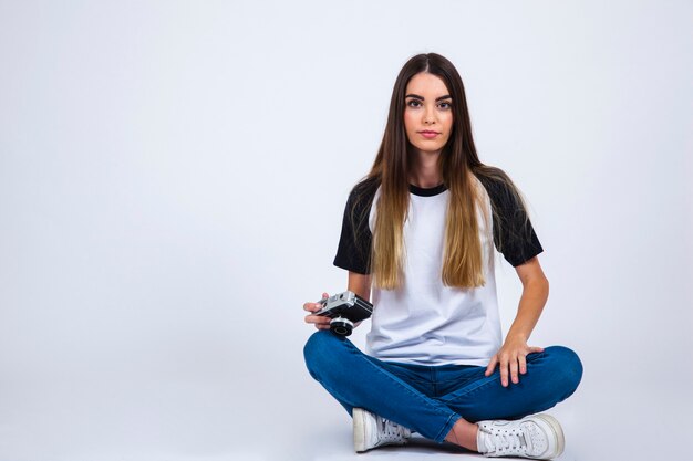 Jeune fille posant avec une caméra sur le sol