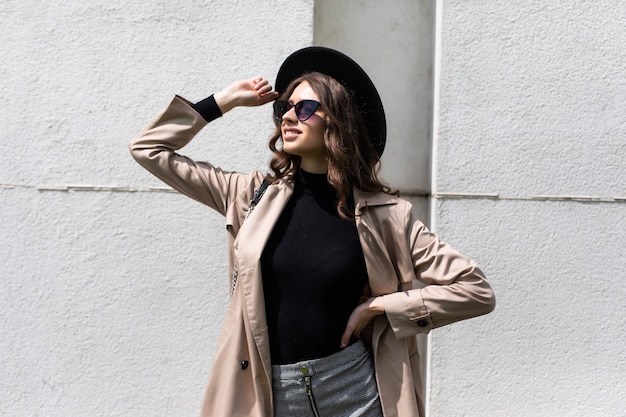 Jeune fille posant dans la rue à la journée ensoleillée, s'amuser seul, élégant chapeau de vêtements vintage et lunettes de soleil. Concept de voyage