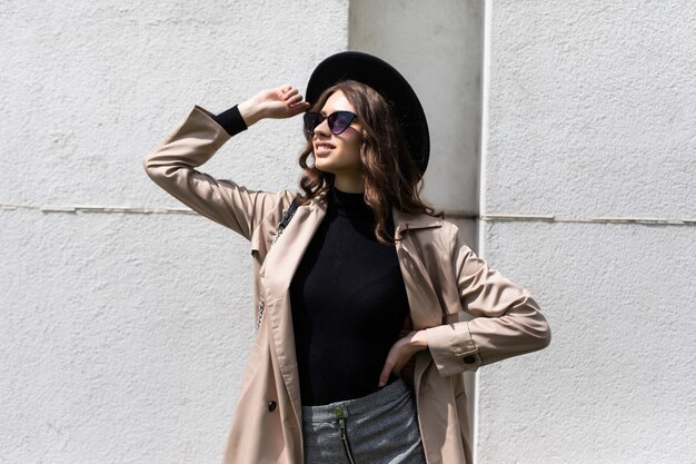 Jeune fille posant dans la rue à la journée ensoleillée, s'amuser seul, élégant chapeau de vêtements vintage et lunettes de soleil. Concept de voyage