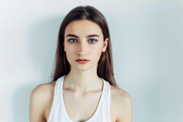 Jeune fille posant devant la caméra sur un fond blanc