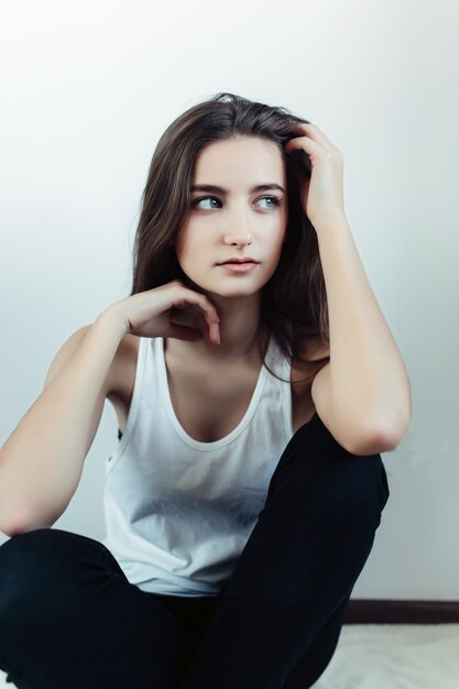 Jeune fille posant devant la caméra sur un fond blanc