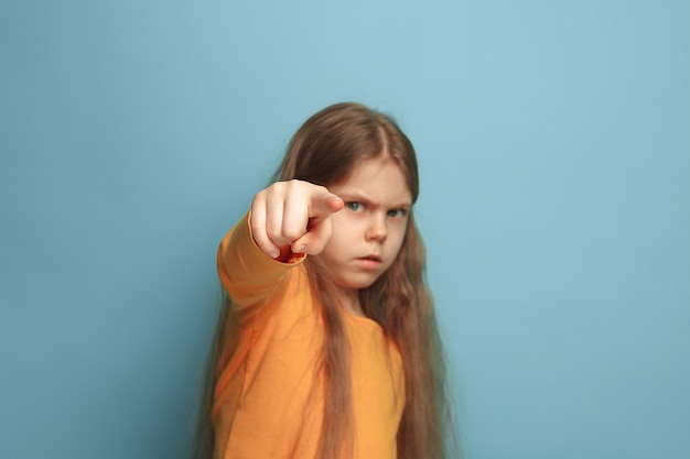 Photo gratuite jeune fille posant et pointant vers l'avant contre le mur bleu