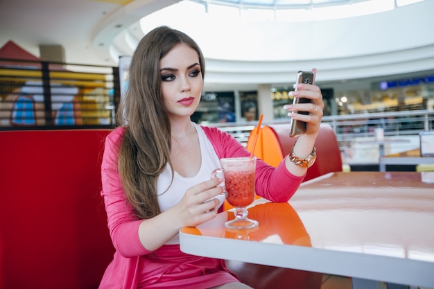 Jeune fille posant avec un téléphone et un soda