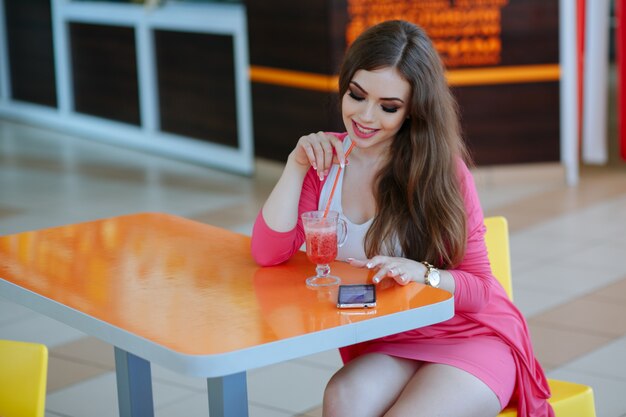Jeune fille posant avec un téléphone et un soda