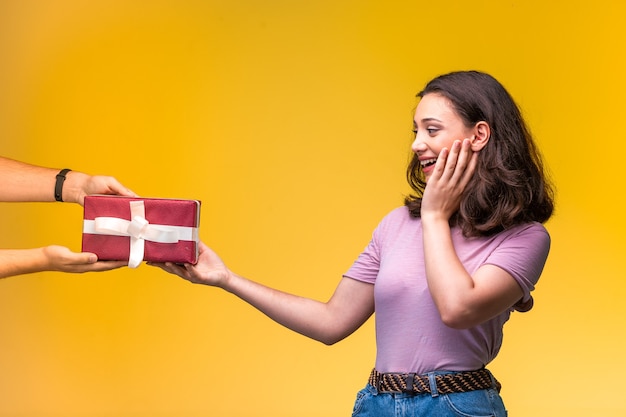 Jeune fille prenant un coffret cadeau de son amie et surprise.