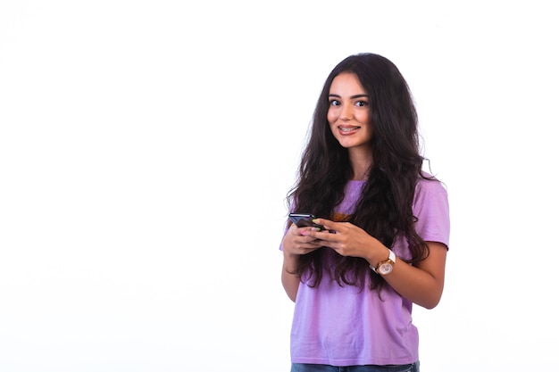 Jeune fille prenant selfie ou faisant un appel vidéo sur fond blanc et souriant