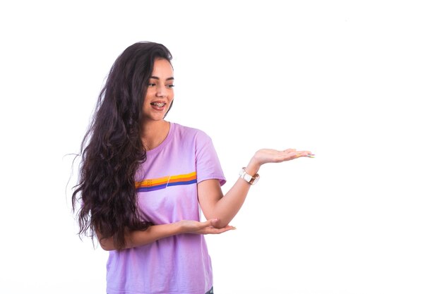 Jeune fille présentant quelque chose avec signe de la main.