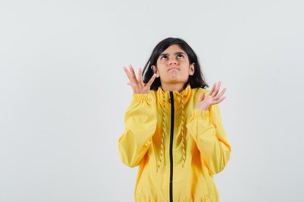 Jeune fille qui s'étend les mains en veste bomber jaune et à la colère