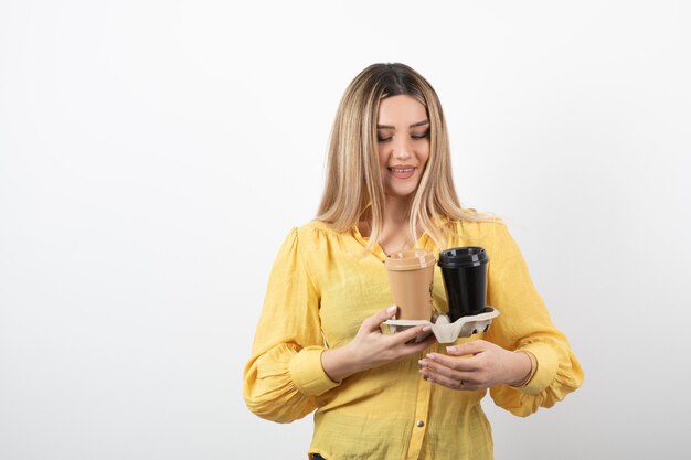 jeune fille regardant des tasses de café sur blanc.