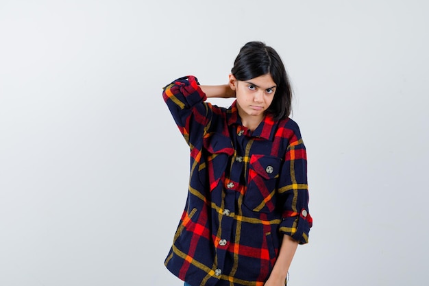 Photo gratuite jeune fille rentrant les cheveux tout en posant en chemise à carreaux et charmante. vue de face.