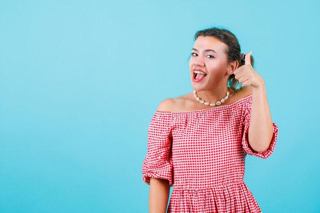 La jeune fille riante montre le geste parfait sur le fond bleu