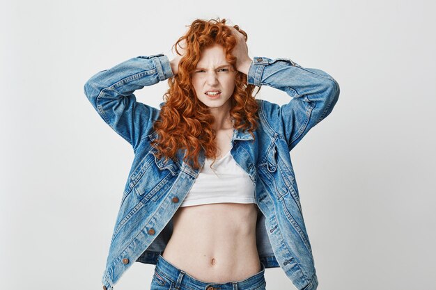 Jeune fille rousse cool mécontente, saisissant la tête.